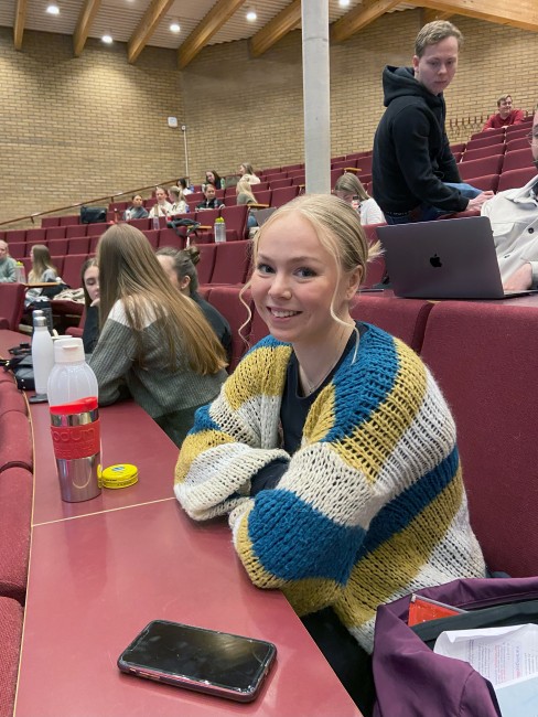 Smilende kvinnelig student i auditorium.