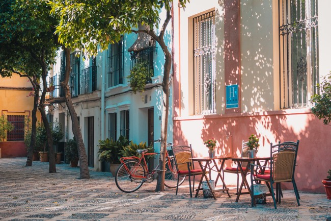 Gate i Spania, fargerike bygninger, sykkel ,bord og to stoler 