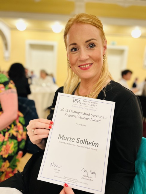 Smilende kvinne viser frem diplom med påskrift "Marte Solheim"