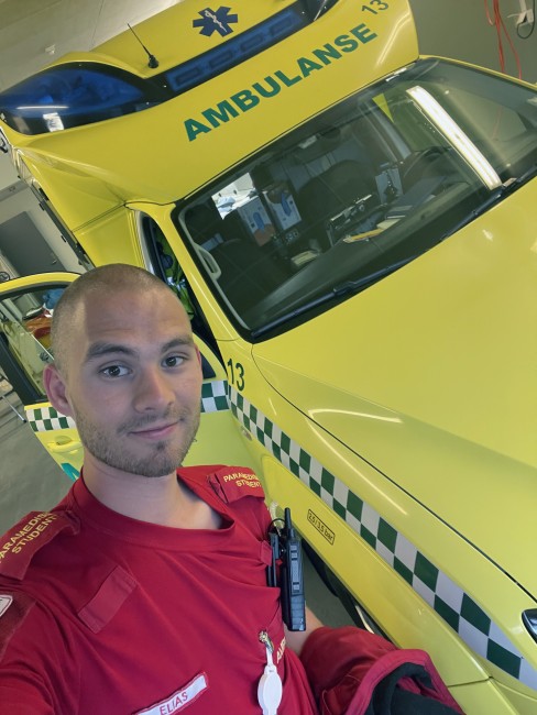Paramedisinstudent i uniform foran ambulansebil