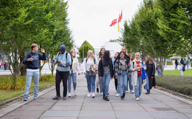 En gruppe med studenter går samlet nedover campus.