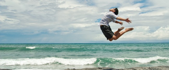 Ung mann hopper høyt på stranden