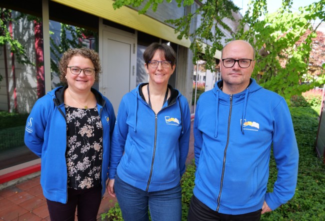 Tre ansatte med blå hettegenser