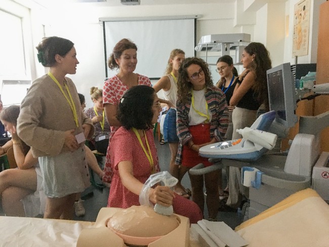Lærer og jordmorstudenter i undervisning i bruk av ultralydapparat. Ferdighetstreningen gjennomføres på en simuleringsdukke.