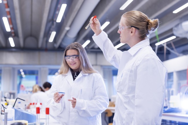 To personer ikledd laboratoriefrakker jobber på et laboratorium. Foto.