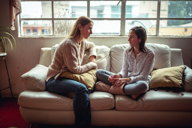 Mor og datter sitter i sofaen og snakker alvorlig sammen.