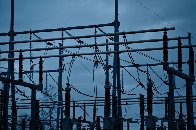 Electricity substation structures silhouetted against a steel grey, cloudy sky