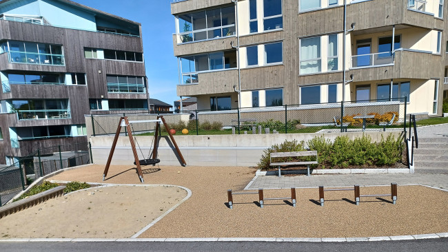 Lekeplass med boligblokker i bakgrunnen.